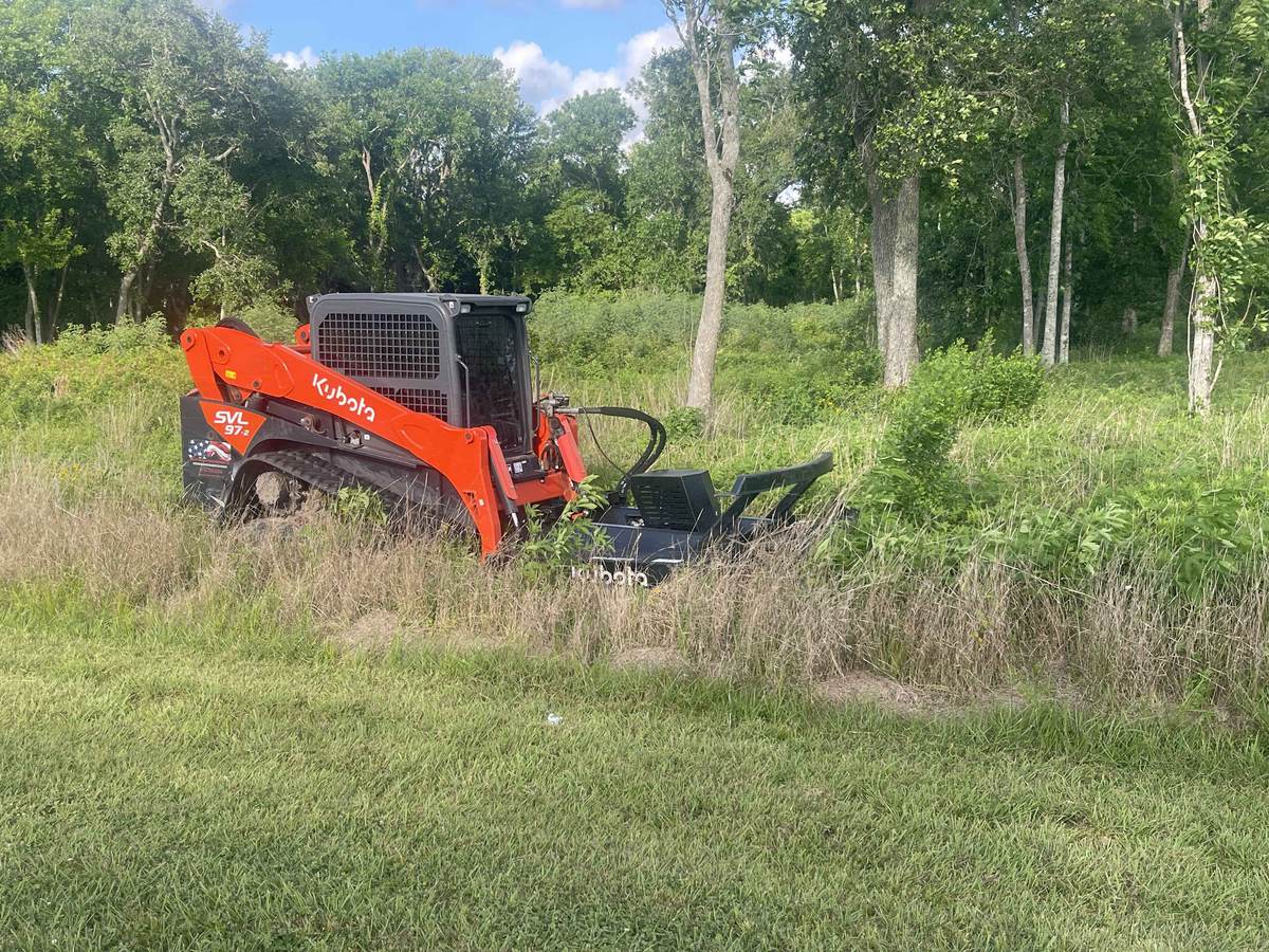 Kubota compact track loader with a mulching head clearing thick brush